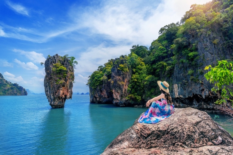 Beautiful girl sitting on the rock at James Bond island in Phang nga, Thailand.